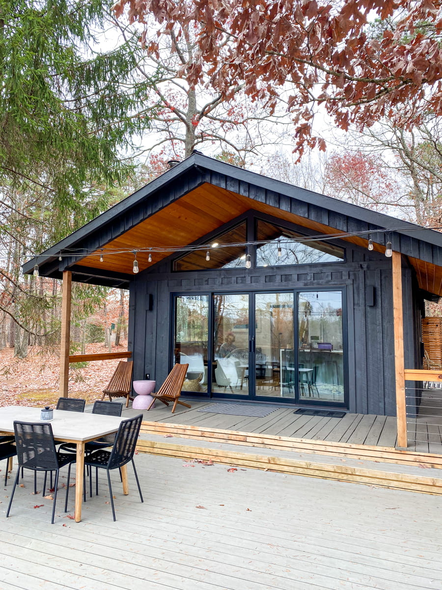 A black exterior of a cabin with an awning and outdoor seating in front