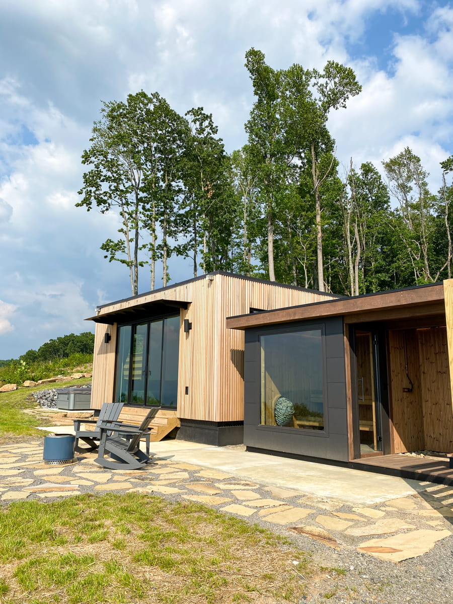 A Scandinavian style tiny house with a sauna, outdoor shower, fire pit and two Adirondack chairs
