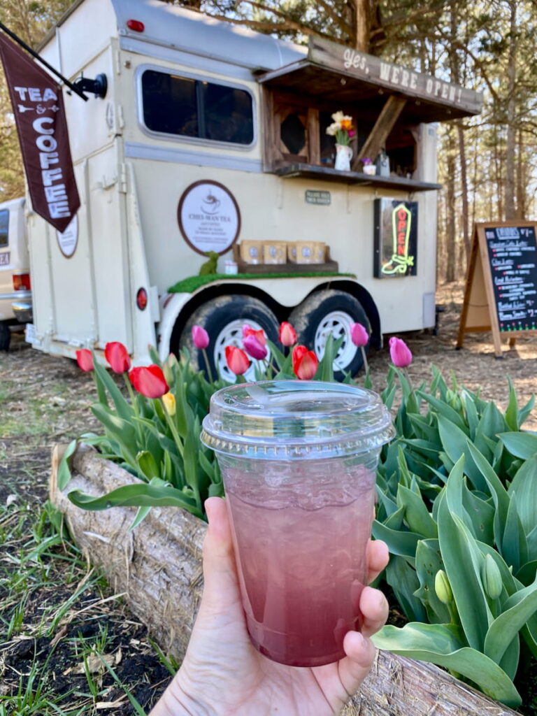 Holding a cup of lemonade in front of the Cheiman Tea drink truck