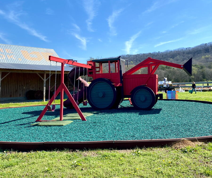 A custom made playground that looks like a tractor with a swings