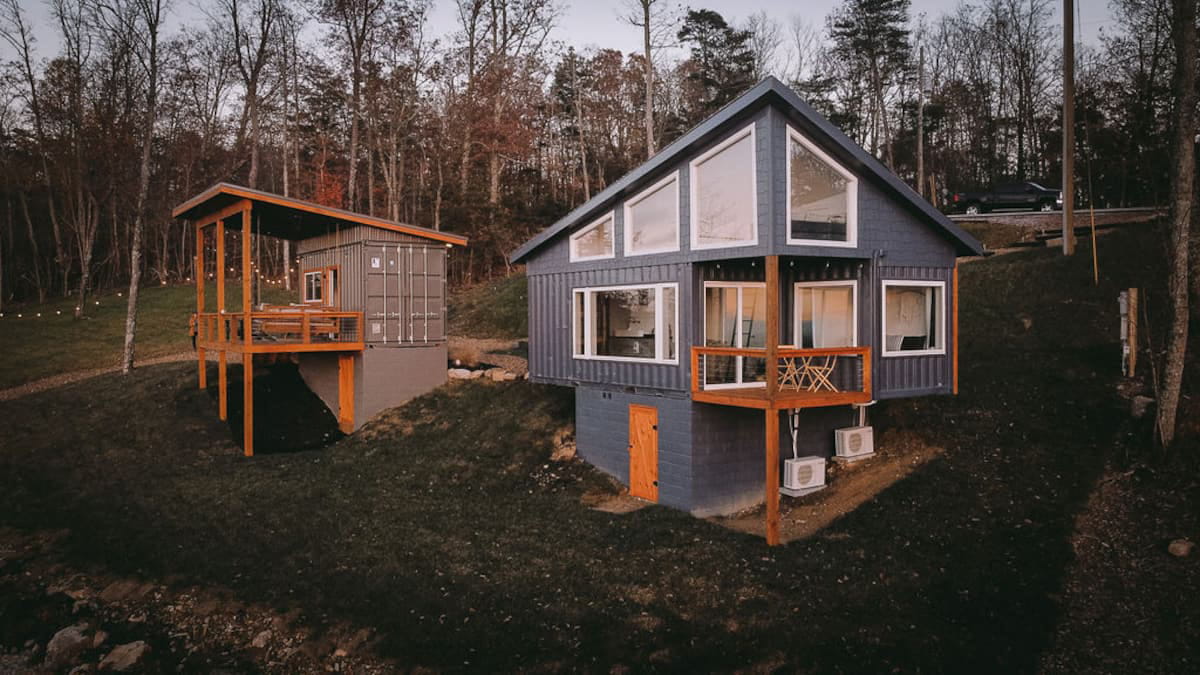 Two shipping containers are perched on the edge of the mountain with windows and orange porches
