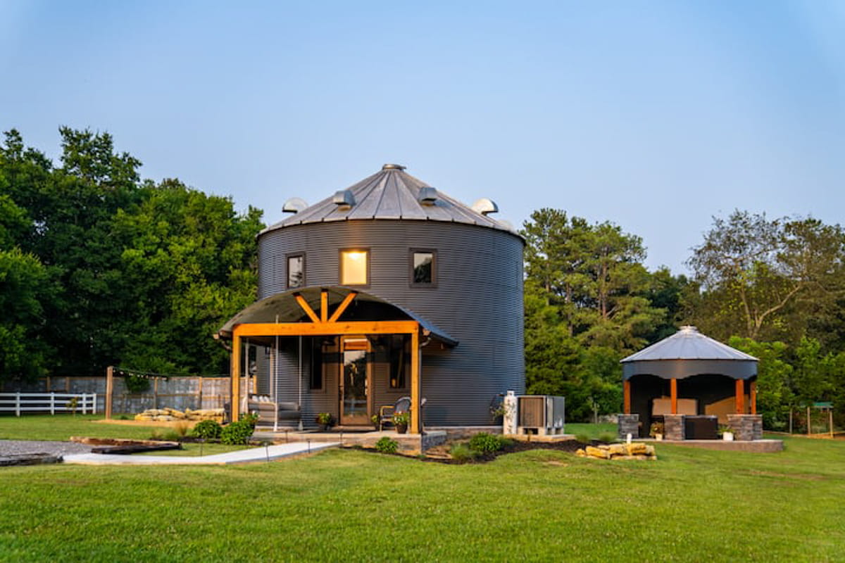 A large gray silo with awning and a smaller building beside it
