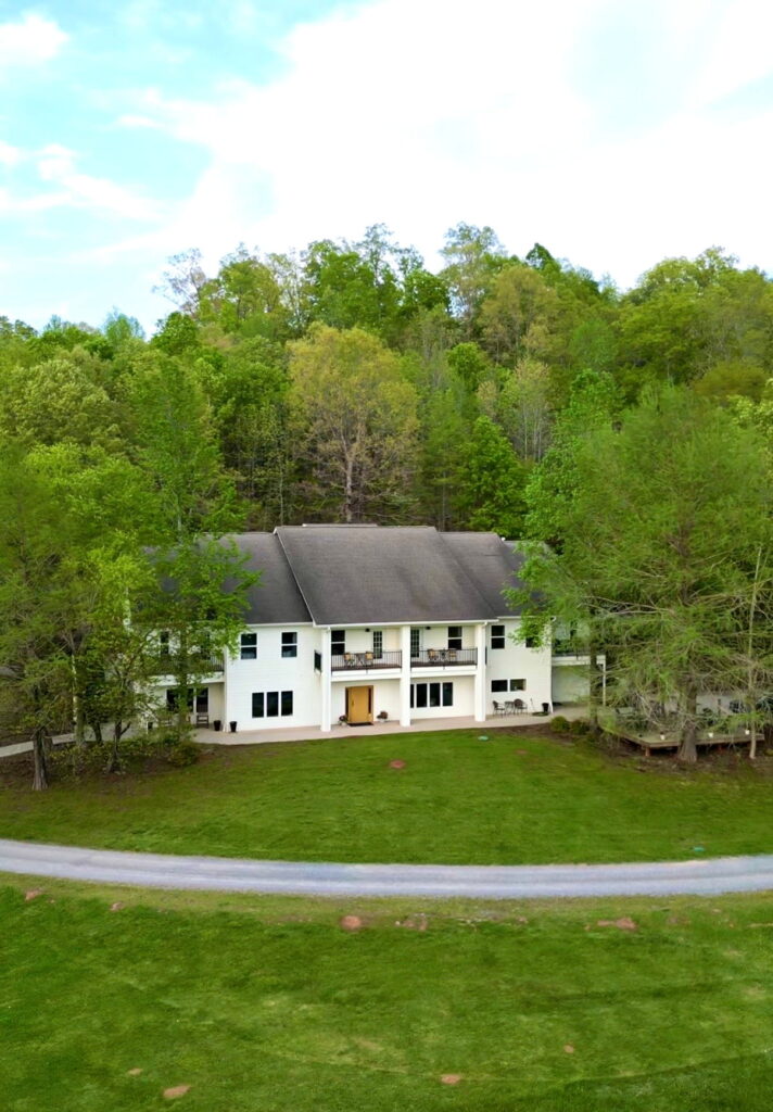 a white lodge with woods surrounding it