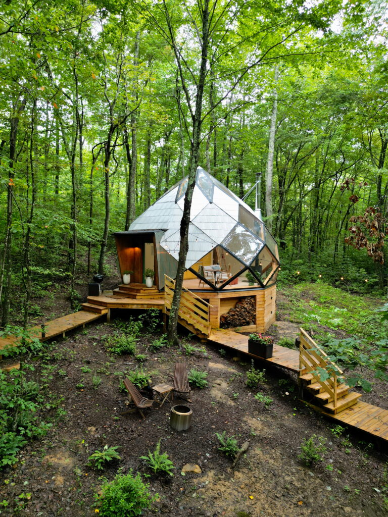 a custom made Zome airbnb surrounded by lush forest, a fire pit, and stairs 
